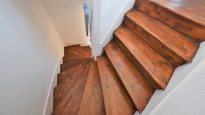 Un escalier en bois, avec des murs blancs et une rampe bleue.