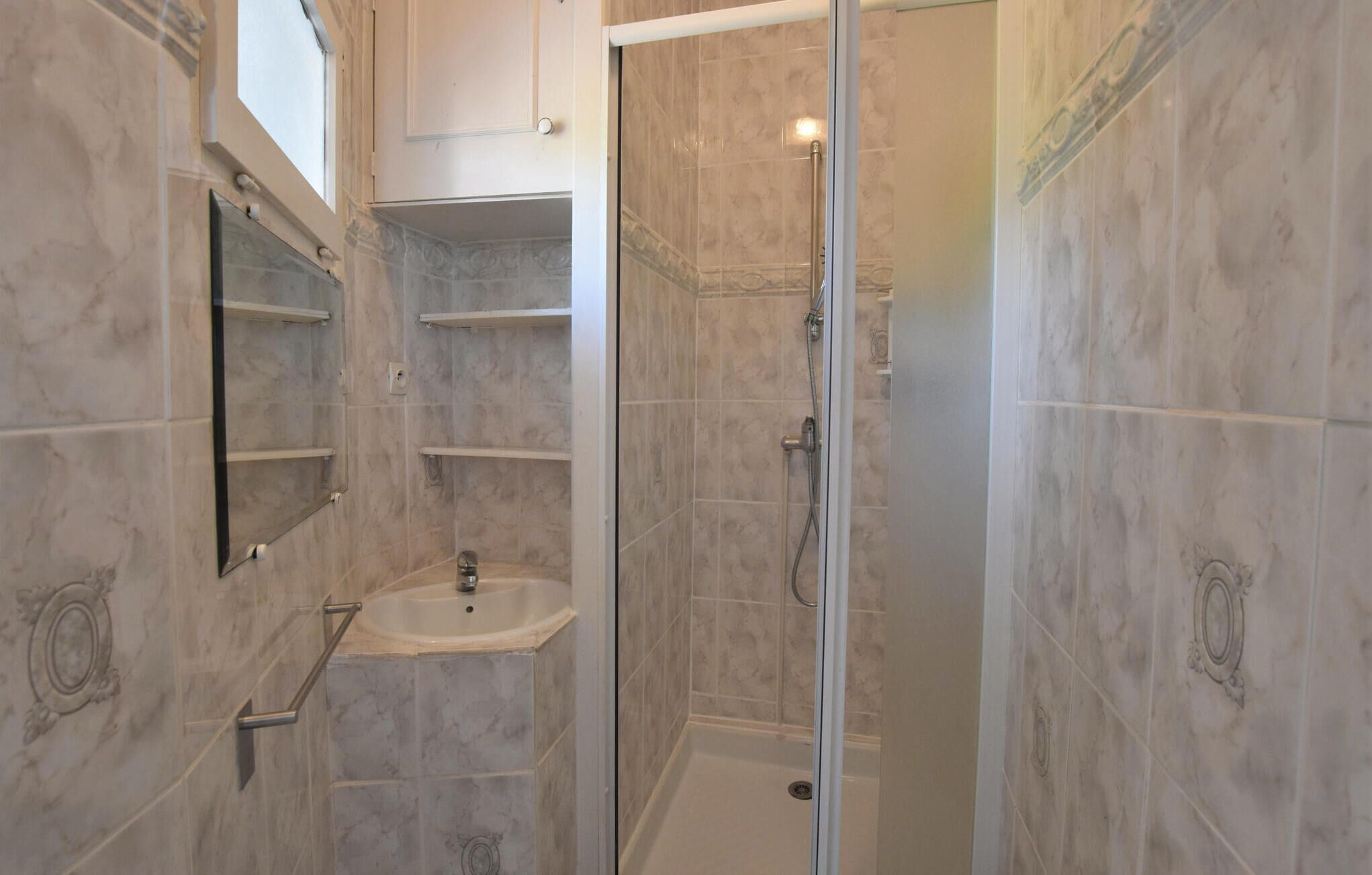A bathroom with a sink, mirror, and shower.