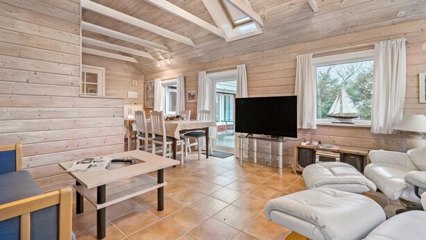 A cozy cabin interior with a dining area, a living room with a TV, and a large window with a sailboat model. - Amazing home in Skjern with kitchen (Skjern)