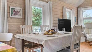 A wooden cabin interior with a dining table set for four, a television, and a framed butterfly picture on the wall. - Amazing home in Skjern with kitchen (Skjern)