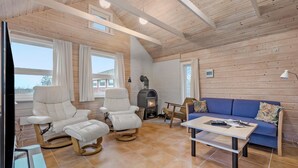 A cozy cabin interior with a fireplace, a blue sofa, and two white armchairs. - Amazing home in Skjern with kitchen (Skjern)