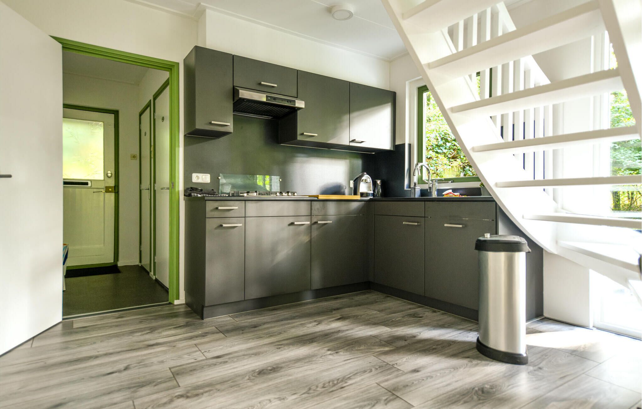 A modern kitchen with grey cabinets, stainless steel appliances, and a large window.