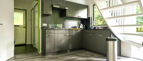 A modern kitchen with grey cabinets, stainless steel appliances, and a large window.