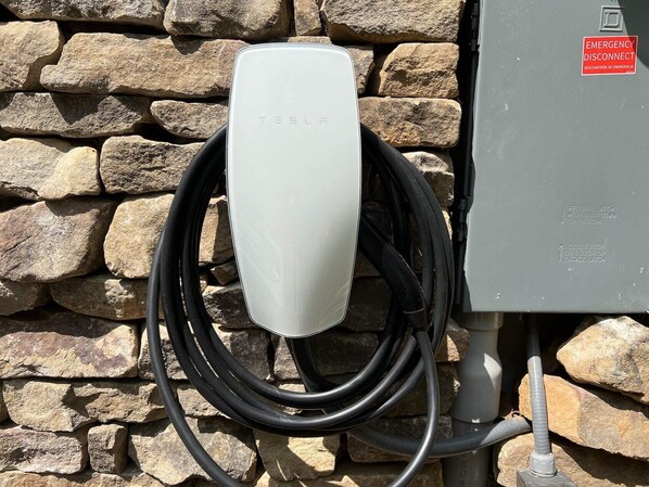 A Tesla charging station mounted on a stone wall.