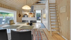 Une cuisine moderne dotée d’un îlot central, de murs en bois et d’un escalier menant à un niveau supérieur.