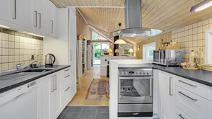 Une cuisine moderne avec des meubles blancs, un lave-vaisselle Bosch, un four Armstrong et un plafond en bois.