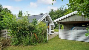 Une petite maison de plain-pied, dotée d’un toit en pente et d’une terrasse en bois.