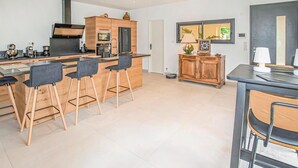 A modern kitchen with a central island, bar stools, and a dining table. - Beautiful home in Robion (Robion)