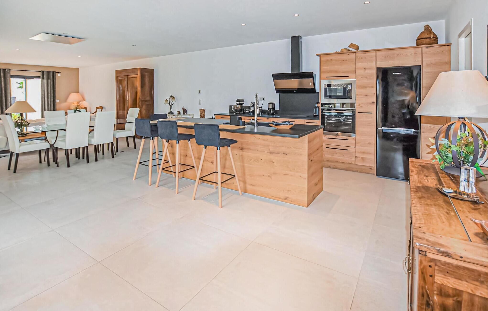 A modern kitchen with a central island, wooden cabinetry, and stainless steel appliances.