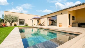 A modern outdoor pool area with a wooden deck, a lounge chair, and a pergola with an umbrella. - Beautiful home in Robion (Robion)