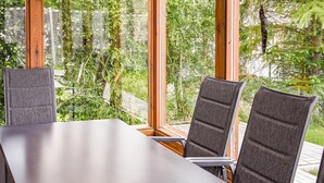 Ein Konferenztisch mit drei Stühlen, großen Fenstern und Blick ins Grüne.