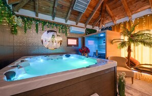 Zona de spa con bañera de hidromasaje, techo de madera y televisor montado en la pared.
