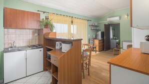 Une cuisine compacte équipée d’un évier, d’une cuisinière et de meubles de rangement en bois. On y trouve également un coin repas avec une table et des chaises.