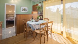 Un coin repas avec une table ronde, des chaises en bois, une petite plante en pot et une bouteille de vin.