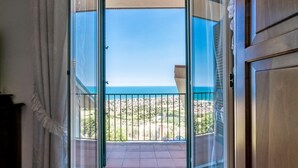 Un balcón con vistas despejadas al mar y un patio empedrado.