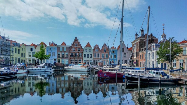 Een jachthaven met afgemeerde boten, omringd door kleurrijke historische gebouwen.