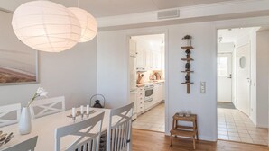 A modern kitchen with white cabinets, a wooden countertop, and a hanging light fixture.