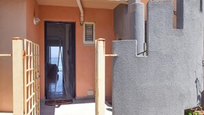 A narrow entrance with a metal gate, a door with a window, and a concrete wall with a textured surface. - 1 bedroom nice apartment in Marina di Caronia (Marina di Caronia)