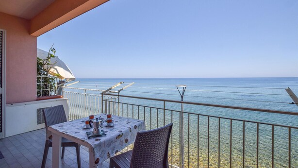 A balcony with a table set for two, overlooking a clear blue sea. - 1 bedroom nice apartment in Marina di Caronia (Marina di Caronia)