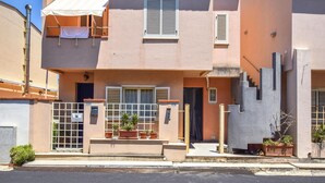 A two-story building with a beige facade, a small front garden with potted plants, a metal gate, and a staircase leading to the entrance. - 1 bedroom nice apartment in Marina di Caronia (Marina di Caronia)