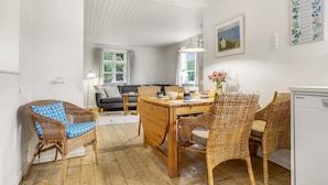 A cozy living room with a sofa, a dining table with chairs, and a kitchen area with a refrigerator.