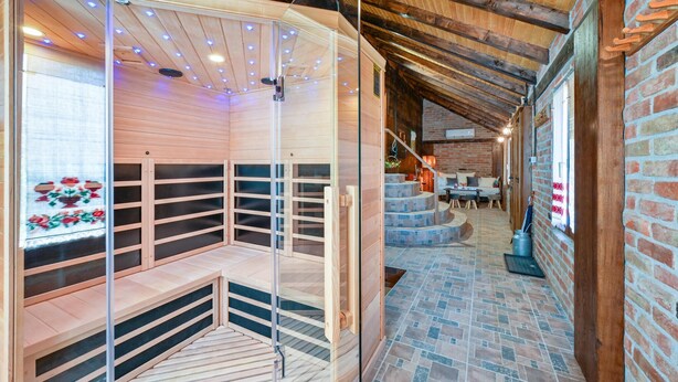 Uma sala de sauna com bancos de madeira e divisórias de vidro, parede de tijolos e chão revestido de azulejos.