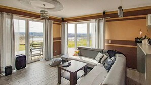 Ein modernes Wohnzimmer mit einer Couch, einem Couchtisch und Blick auf einen Park durch große Fenster.