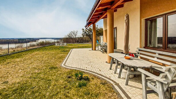 Eine Terrassenfläche mit Tisch und Bänken mit Blick auf ein Gewässer.