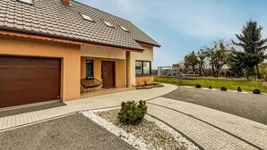 Ein zweistöckiges Haus mit Ziegeldach, einer Veranda und einer Auffahrt zu einem verschlossenen Eingang.