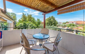 Un espacio de estar al aire libre con techo, con una mesa y sillas, con vistas a un barrio residencial.
