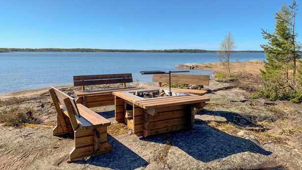 Een houten terras met banken en een tafel aan een meer.