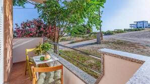 A balcony with a chair, a small table with a watermelon and a glass, and a view of a road and buildings. - Amazing apartment in Medulin with WiFi (Medulin)