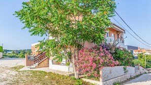 A modern two-story house with a staircase leading to the entrance, surrounded by lush greenery and flowering plants. - Amazing apartment in Medulin with WiFi (Medulin)