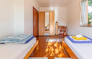Ein Schlafzimmer mit zwei Betten, einem Holzschrank, einem Schreibtisch und einem Spiegel.