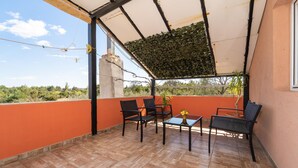 A covered outdoor patio with a table and chairs, a potted plant, and a view of the surrounding landscape. - Beach front apartment in Benkovac with WiFi (Benkovac)