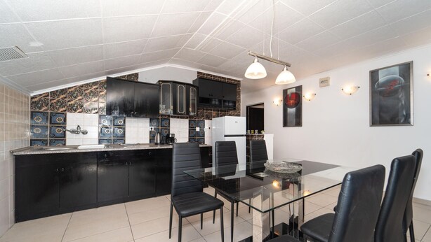 A modern kitchen with black cabinets, a glass dining table, and black chairs. There is a refrigerator, a coffee maker, and a kettle on the counter. - Beach front apartment in Benkovac with WiFi (Benkovac)
