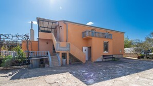 A two-story building with a staircase leading to the upper floor, a balcony on the second floor, and a paved courtyard. - Beach front apartment in Benkovac with WiFi (Benkovac)