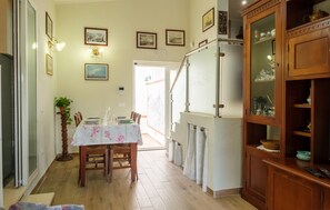 A dining area with a table set for four, a wooden cabinet with glass doors, and a staircase leading to an upper level.