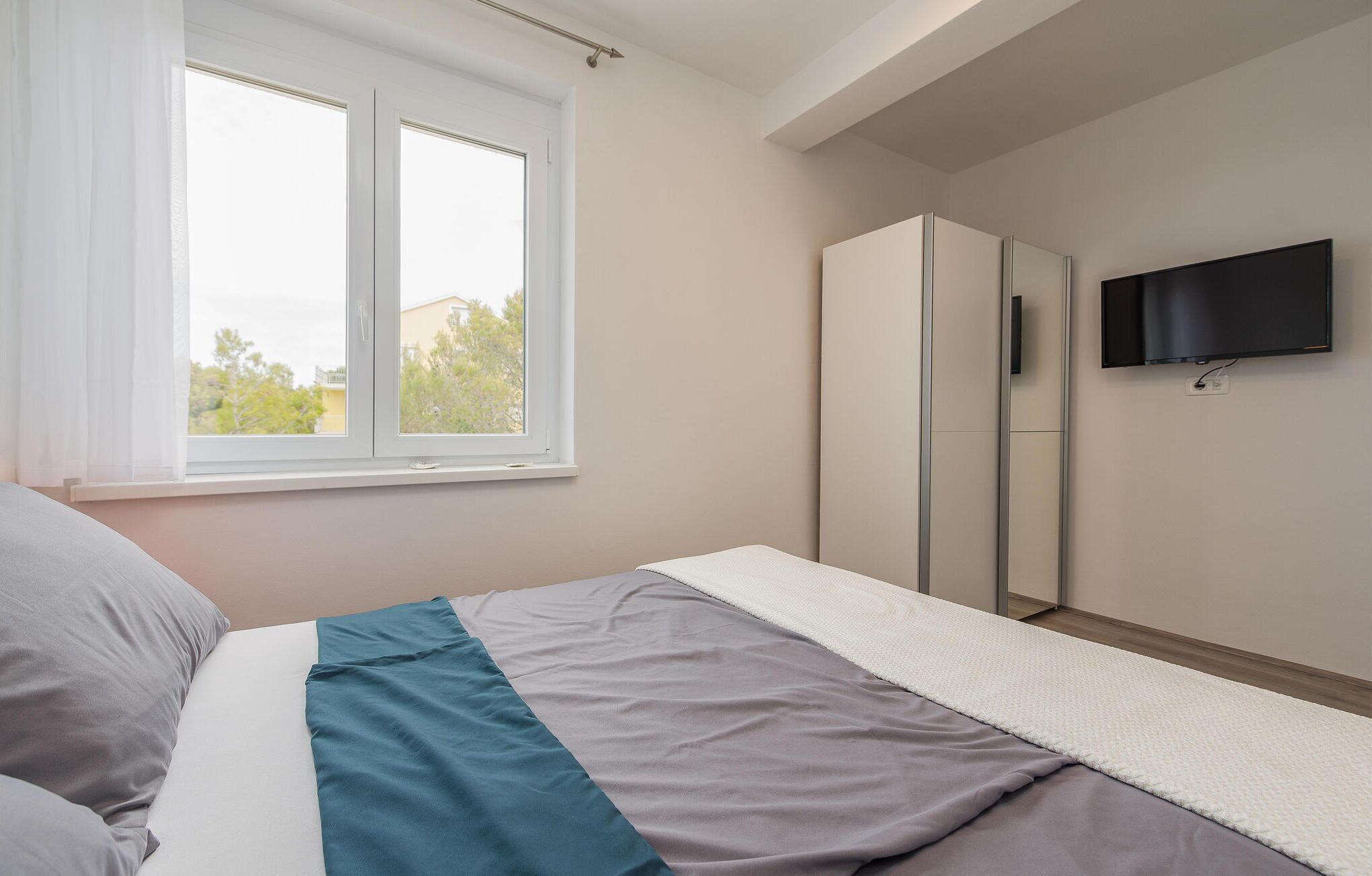 Ein Schlafzimmer mit Bett, Fenster, Kleiderschrank und Fernseher.