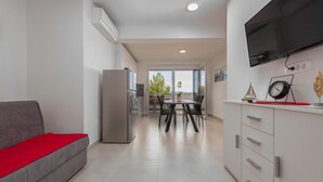 A modern kitchen with a refrigerator, dining table, chairs, and a TV mounted on the wall. - 1 bedroom amazing apartment in Bibinje (Bibinje)