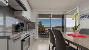 A modern kitchen with a dining area, large windows, and a view of the outdoors. - 1 bedroom amazing apartment in Bibinje (Bibinje)