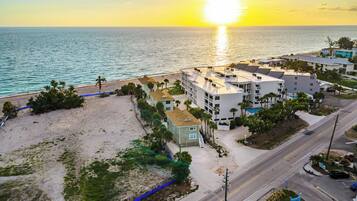 A coastal hotel with multiple buildings, a beach, and a road.