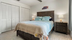 Ein Schlafzimmer mit einem Bett, Nachttischen, einem Deckenventilator und einer Wanddekoration mit Fischen.