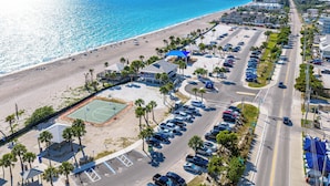 Luftaufnahme einer Küstenlandschaft mit Strand, Parkplatz und Gebäuden.