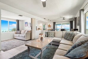 A spacious living room with a large sofa, a coffee table, and a view of the ocean. - Directly On The Beach, Oceanfront Condo with Beautiful Views of the Gulf! (Englewood)
