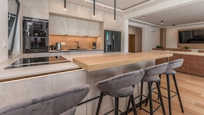 Een moderne keuken met een centraal eiland, barkrukken en een ingebouwde oven.