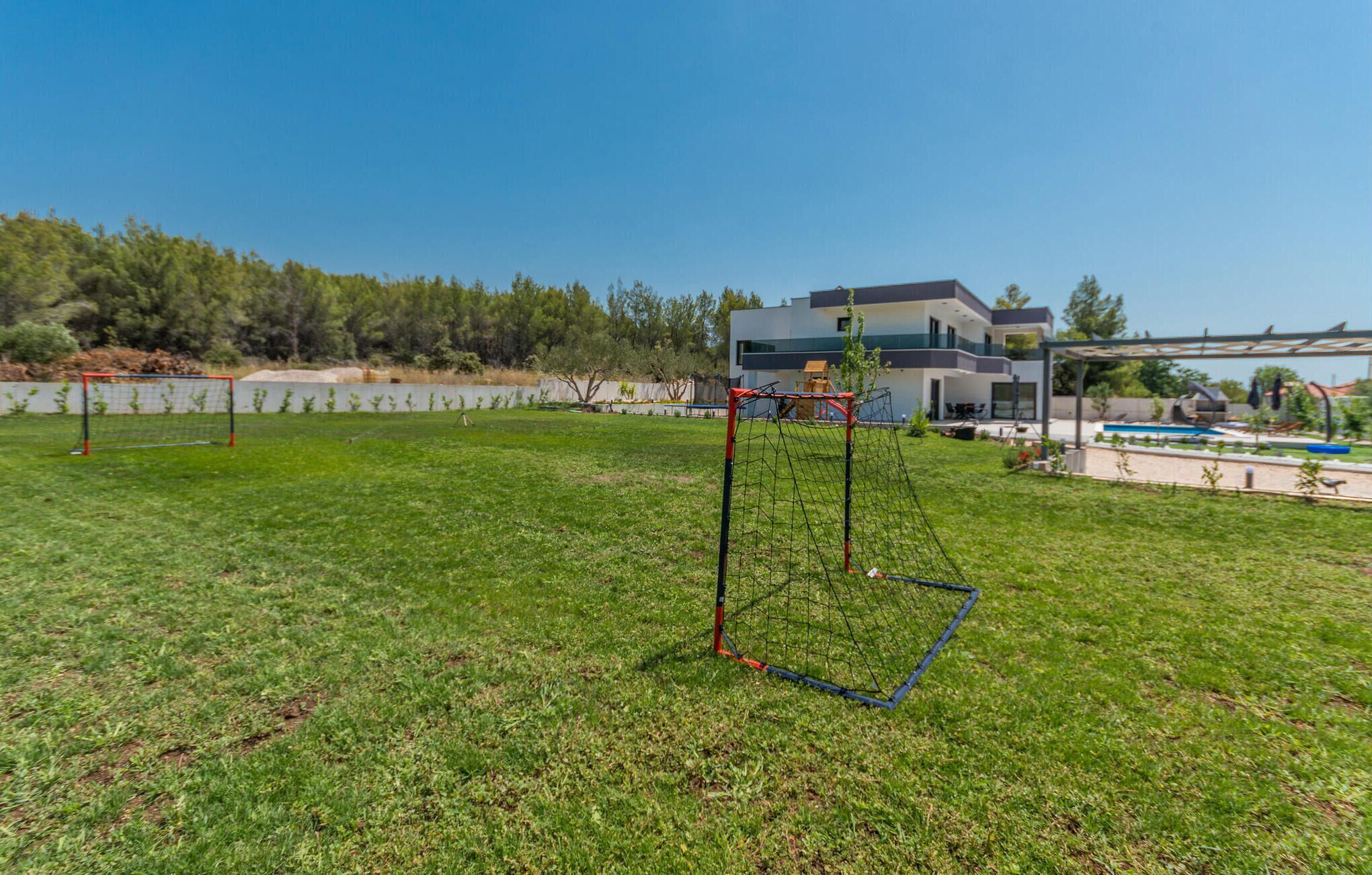 Un espacio al aire libre con césped, un arco de fútbol y un edificio moderno al fondo.