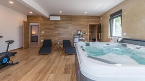Een moderne spa-ruimte met een jacuzzi, houten vloeren en uitzicht op de natuur.