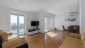 A spacious living room with a large TV, a dining area, and a balcony with a view. - 2 bedroom awesome apartment in Crikvenica (Crikvenica)