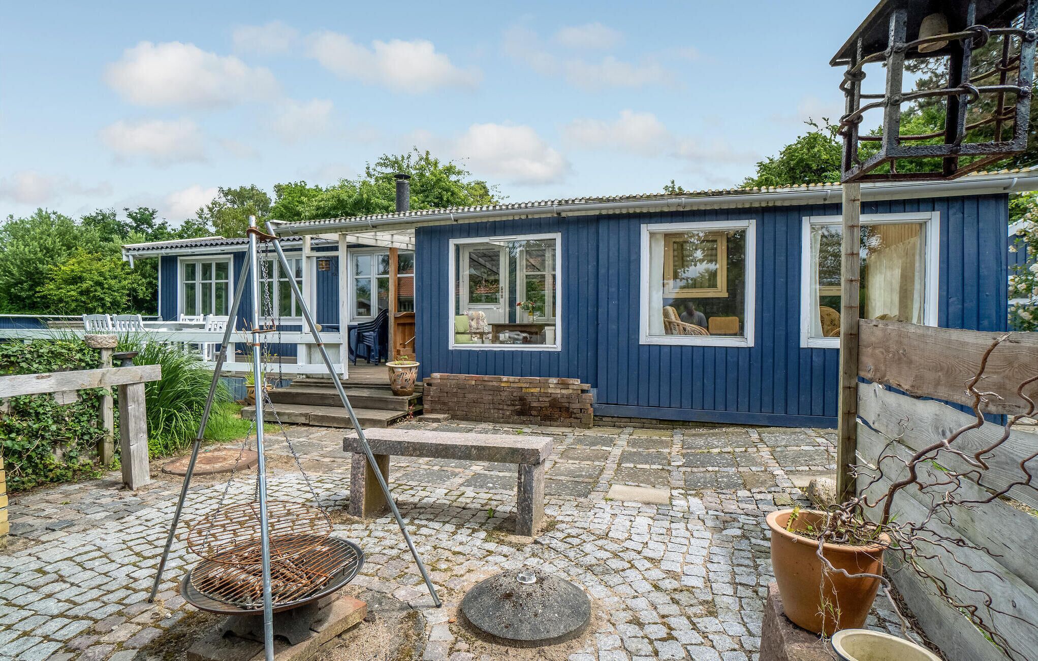 A blue house with a porch, a grill, and a swing set.